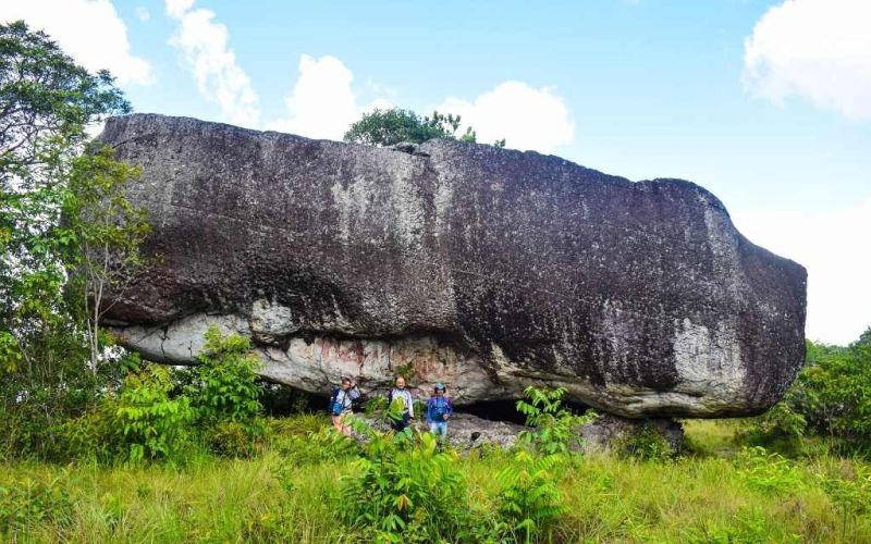 personas debajo de una inmensa roca en tuneles naturales, ello se ven muy chiquitos, turismo guaviare